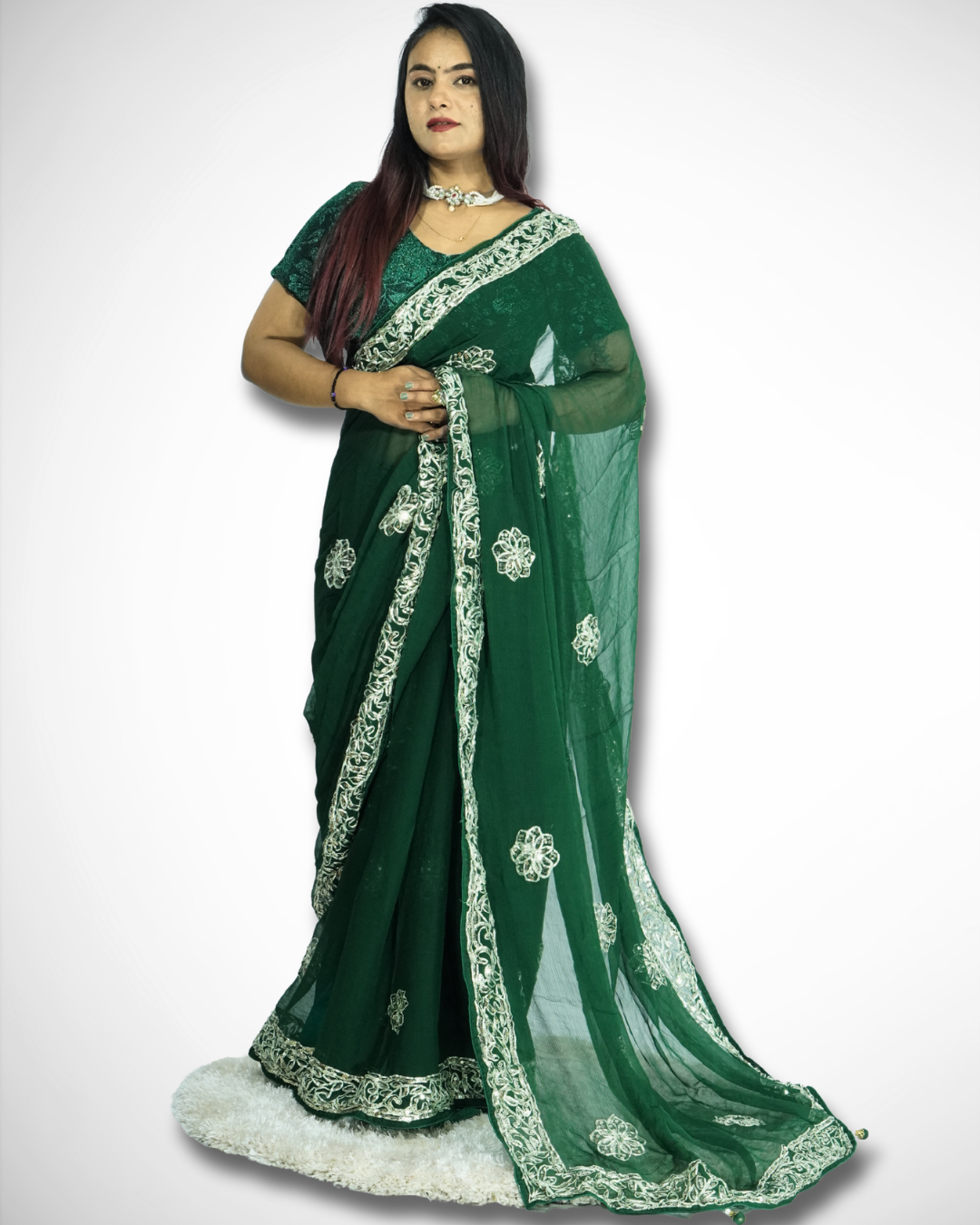 Full-length view of a woman modeling an elegant deep red saree with intricate gold embroidered vine border and scattered floral butta motifs, featuring a sheer flowing pallu and paired with traditional jewelry. ✨