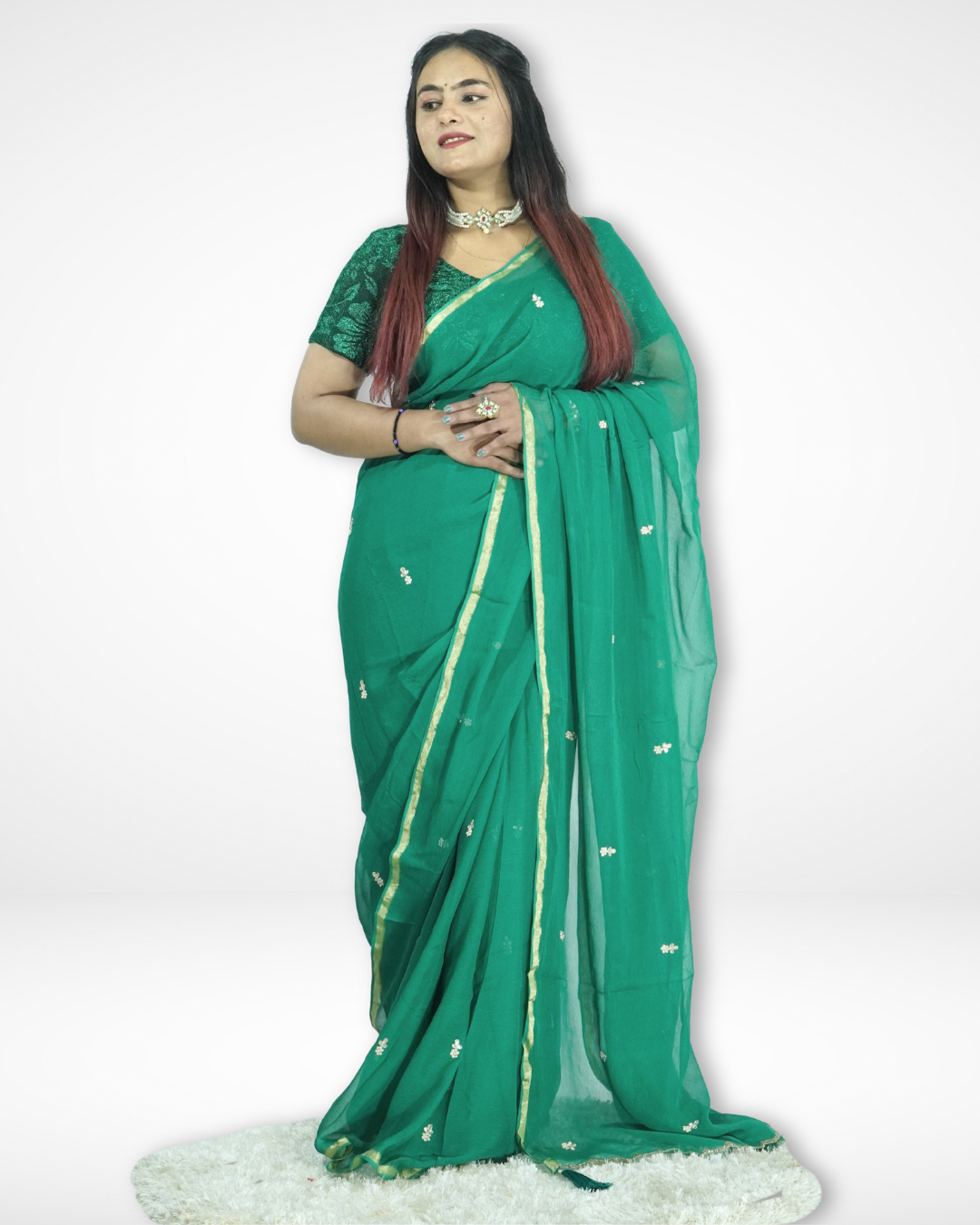 Model wearing an elegant emerald green chiffon saree with delicate zari buti work and a subtle gold border, styled with a matching blouse, showcasing Amai Jaipur’s lightweight festive and occasion wear saree collection.