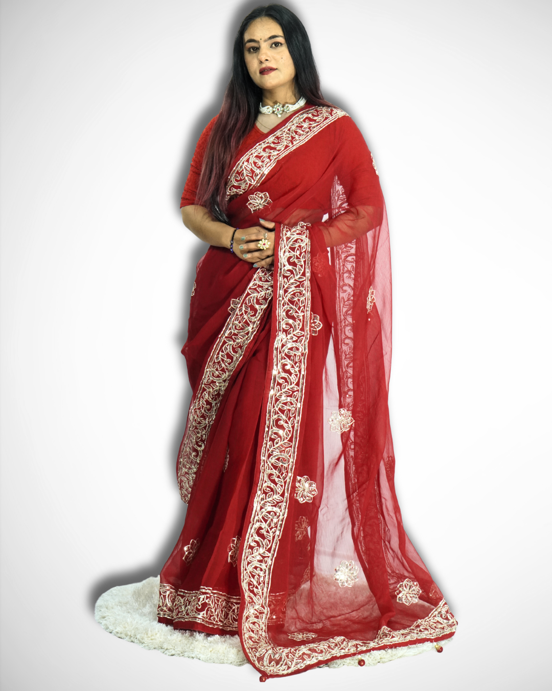 Full-length view of a woman wearing a vibrant red saree with intricate gold embroidered vine border and scattered floral butta motifs, featuring a sheer flowing pallu and styled with traditional jewelry. ✨