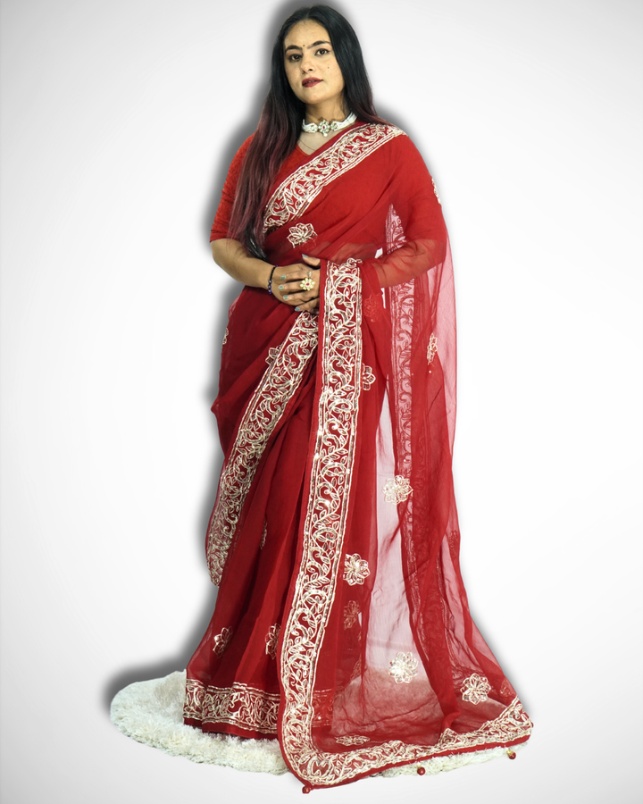 Full-length view of a woman wearing a vibrant red saree with intricate gold embroidered vine border and scattered floral butta motifs, featuring a sheer flowing pallu and styled with traditional jewelry. ✨