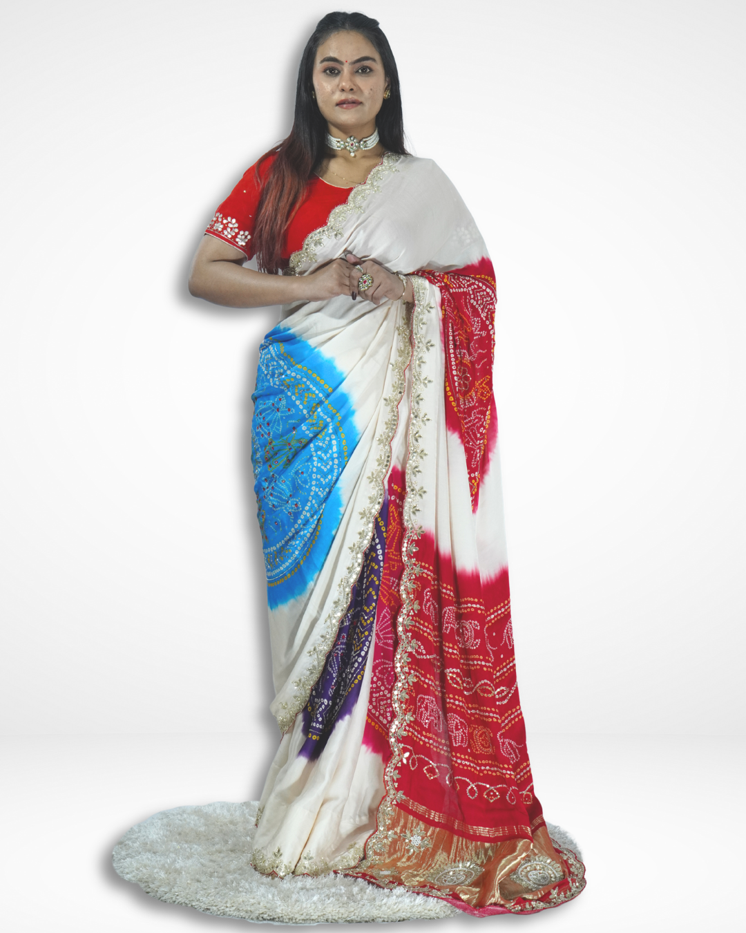 Model wearing a handcrafted ivory saree with vibrant red and blue tie-dye patterns and intricate border detailing, showcasing Amai Jaipur’s sustainable luxury ethnic wear inspired by traditional Jaipur artistry.