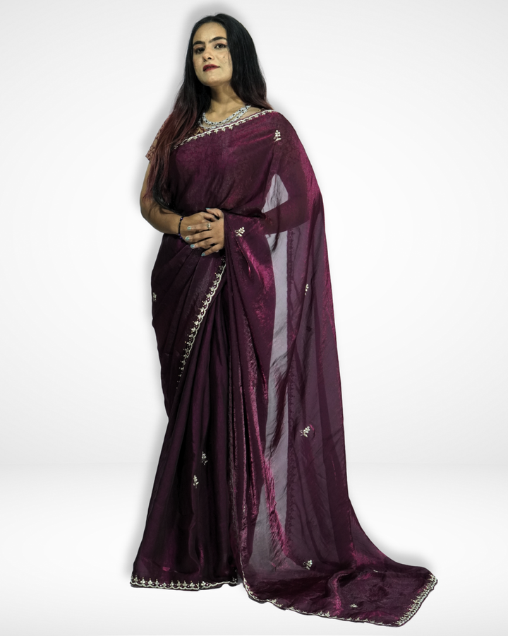 Full-length view of a woman wearing a deep wine-purple saree with subtle shimmer, delicate embroidered motifs, and an elegant border, styled with minimal jewelry for a graceful traditional look. ✨