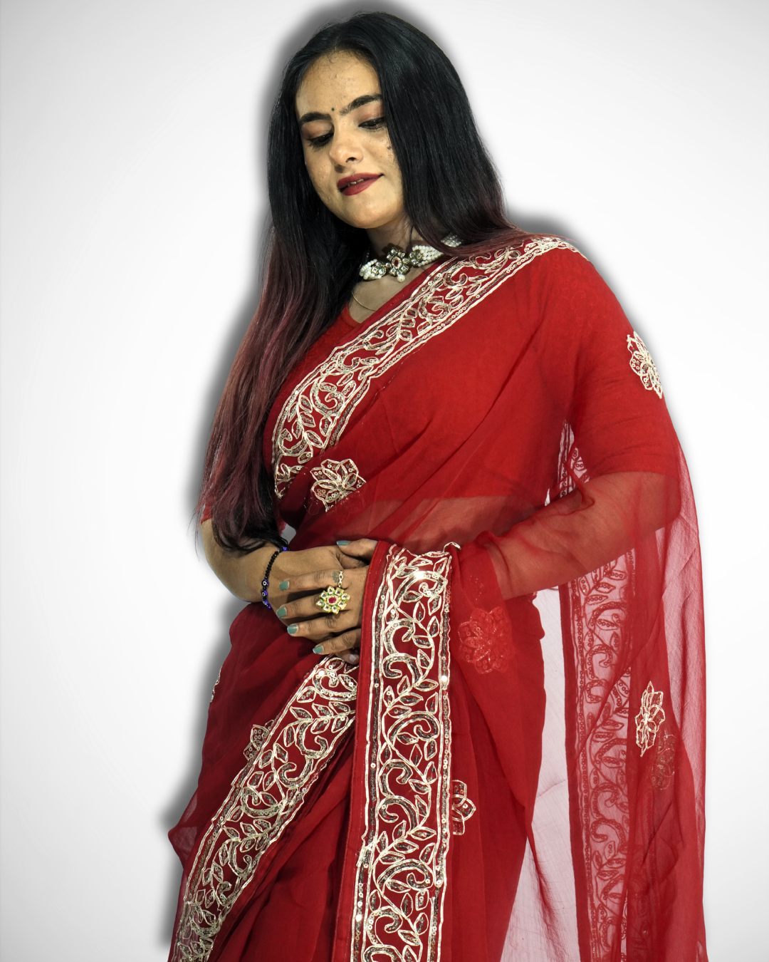 Close-up of a woman wearing a vibrant red saree with intricate gold embroidered vine border and delicate floral butta motifs, highlighting the sheer pallu and detailed craftsmanship paired with traditional jewelry. ✨