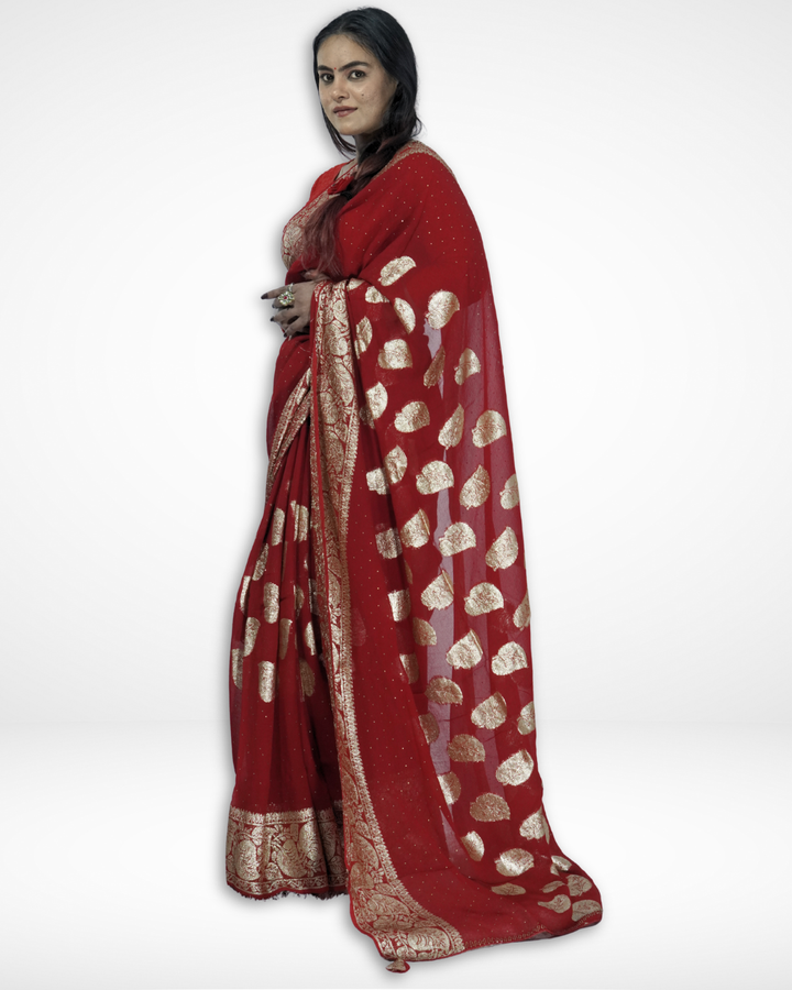 Model showcasing a red Banarasi chiffon saree with gold zari leaf motifs and an intricate woven border, highlighting Amai Jaipur’s handcrafted luxury saree perfect for weddings, bridal wear, and festive ethnic elegance.