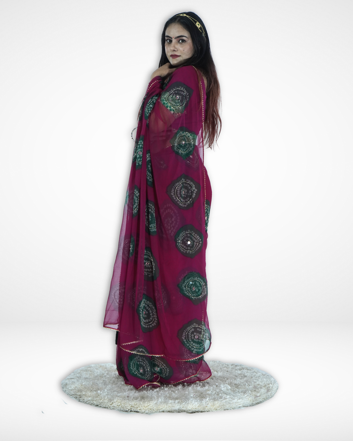 Side view of a model draped in a deep magenta chiffon saree featuring intricate green circular bandhani-inspired motifs and a delicate border, highlighting the graceful flow and festive elegance of Amai Jaipur’s designer saree. ✨