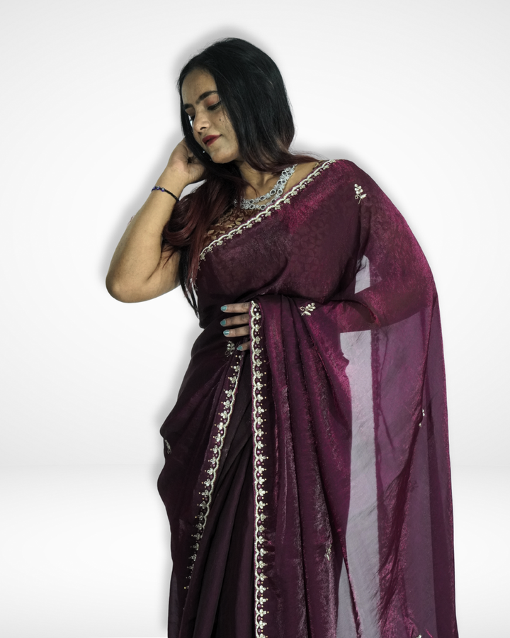 Elegant portrait of a woman wearing a deep wine-purple saree with a subtle shimmer, delicate embroidered border, and small motifs, styled with a statement necklace and graceful drape. ✨