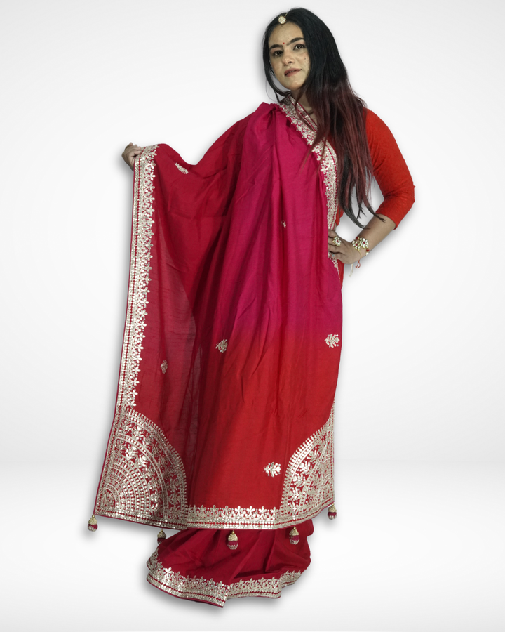 Woman posing in a red saree with detailed gold embroidered borders and tassel accents, holding the pallu to showcase the design, paired with a matching red blouse and traditional jewelry against a plain background. ✨