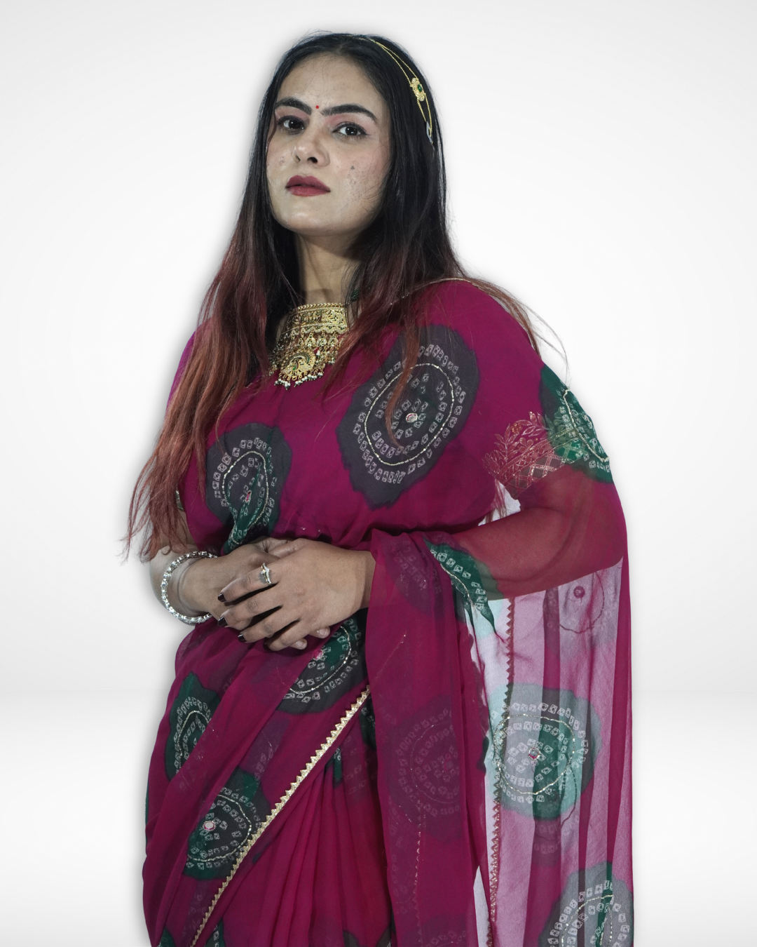 Close-up of a model wearing a deep magenta chiffon saree adorned with green bandhani-style circular motifs and a delicate border, highlighting the elegant drape and festive appeal of Amai Jaipur’s designer ethnic saree. ✨