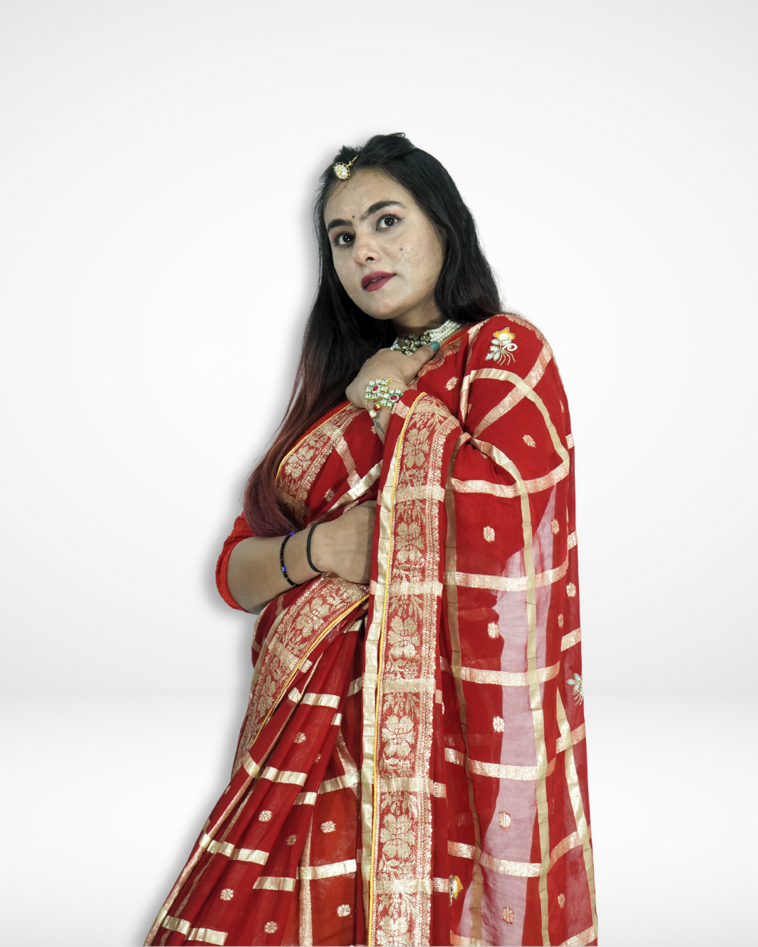 Close-up of a model wearing a rich red saree with an elegant gold checkered pattern, delicate buti motifs, and a detailed zari border, styled with traditional jewelry for a regal festive look by Amai Jaipur. ✨
