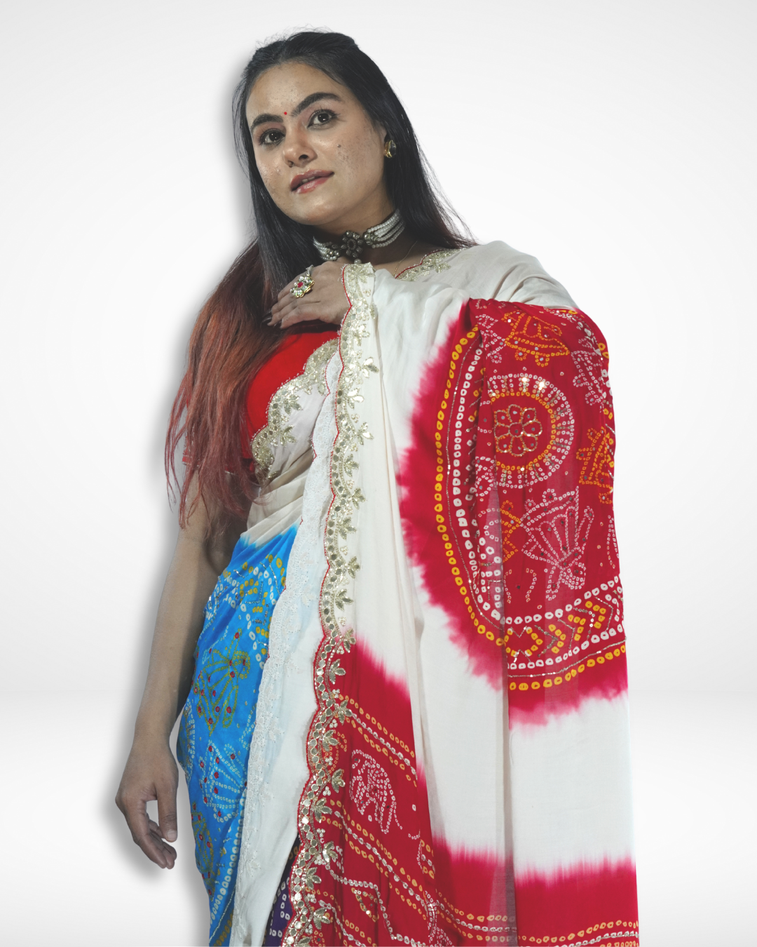 Model wearing an ivory handcrafted saree with vibrant red and blue bandhani-style motifs and delicate gold embroidered border, highlighting Amai Jaipur’s sustainable luxury ethnic wear inspired by traditional Jaipur craftsmanship.