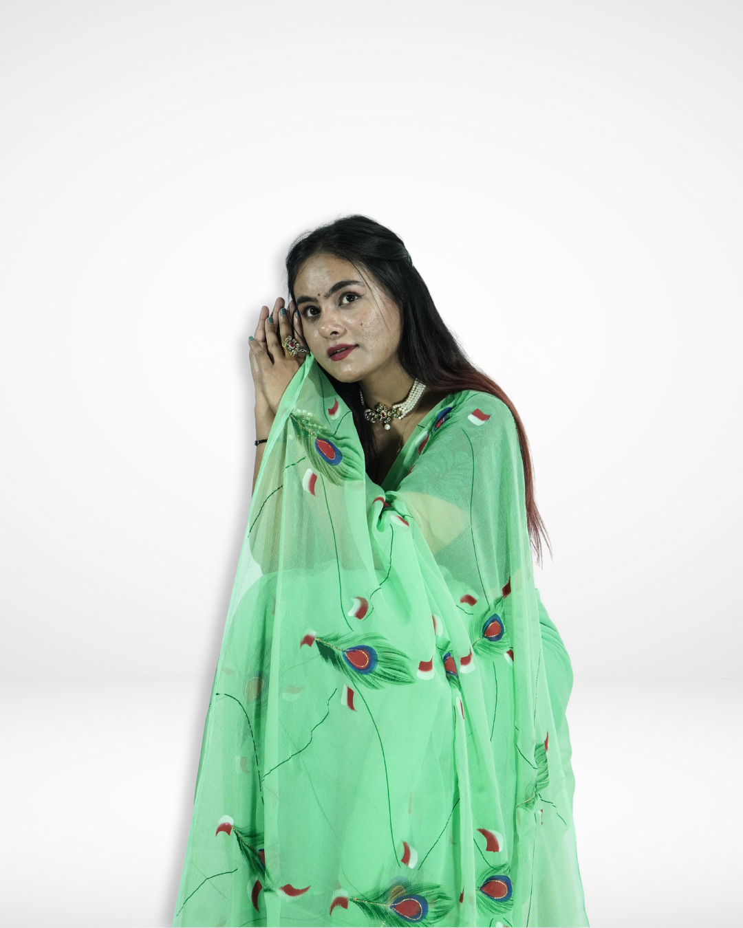 Close-up of a model draped in a mint green chiffon saree with elegant peacock feather prints, showcasing Amai Jaipur’s handcrafted designer saree ideal for festive occasions, wedding celebrations, and graceful ethnic fashion.