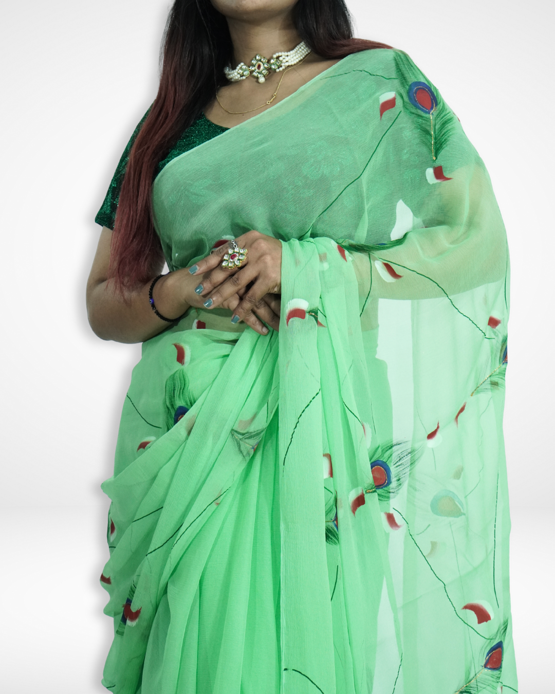 Close-up view of a model wearing a mint green chiffon saree with delicate peacock feather prints and a dark green blouse, highlighting the soft drape and artistic design by Amai Jaipur for elegant festive and occasion wear.