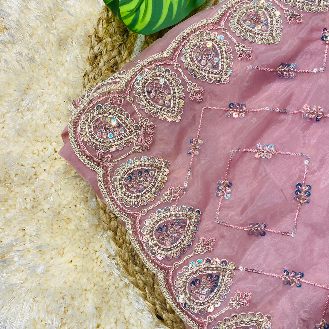 Detailed close-up of a blush pink saree showcasing intricate paisley embroidery along the border, embellished with sequins, beads, and delicate threadwork, with small floral sequin motifs forming a subtle geometric pattern across the fabric. ✨