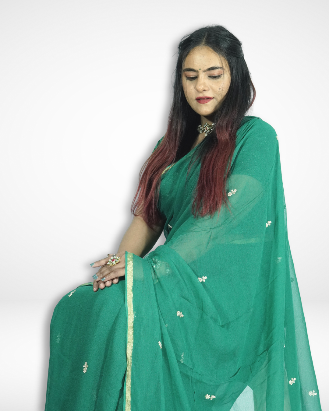 Model posing in an elegant emerald green chiffon saree adorned with delicate floral buti motifs and a refined gold border, styled with statement jewelry for a graceful festive and occasion look by Amai Jaipur. ✨