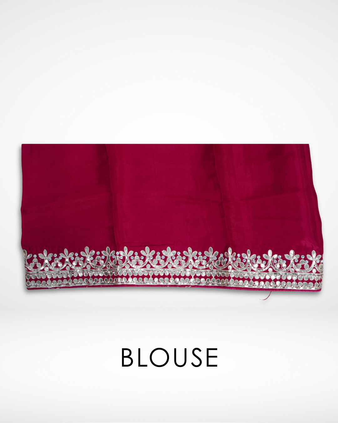 Folded red blouse fabric with a decorative gold embroidered border featuring floral and circular patterns, designed to complement a red saree, displayed against a plain background. ✨