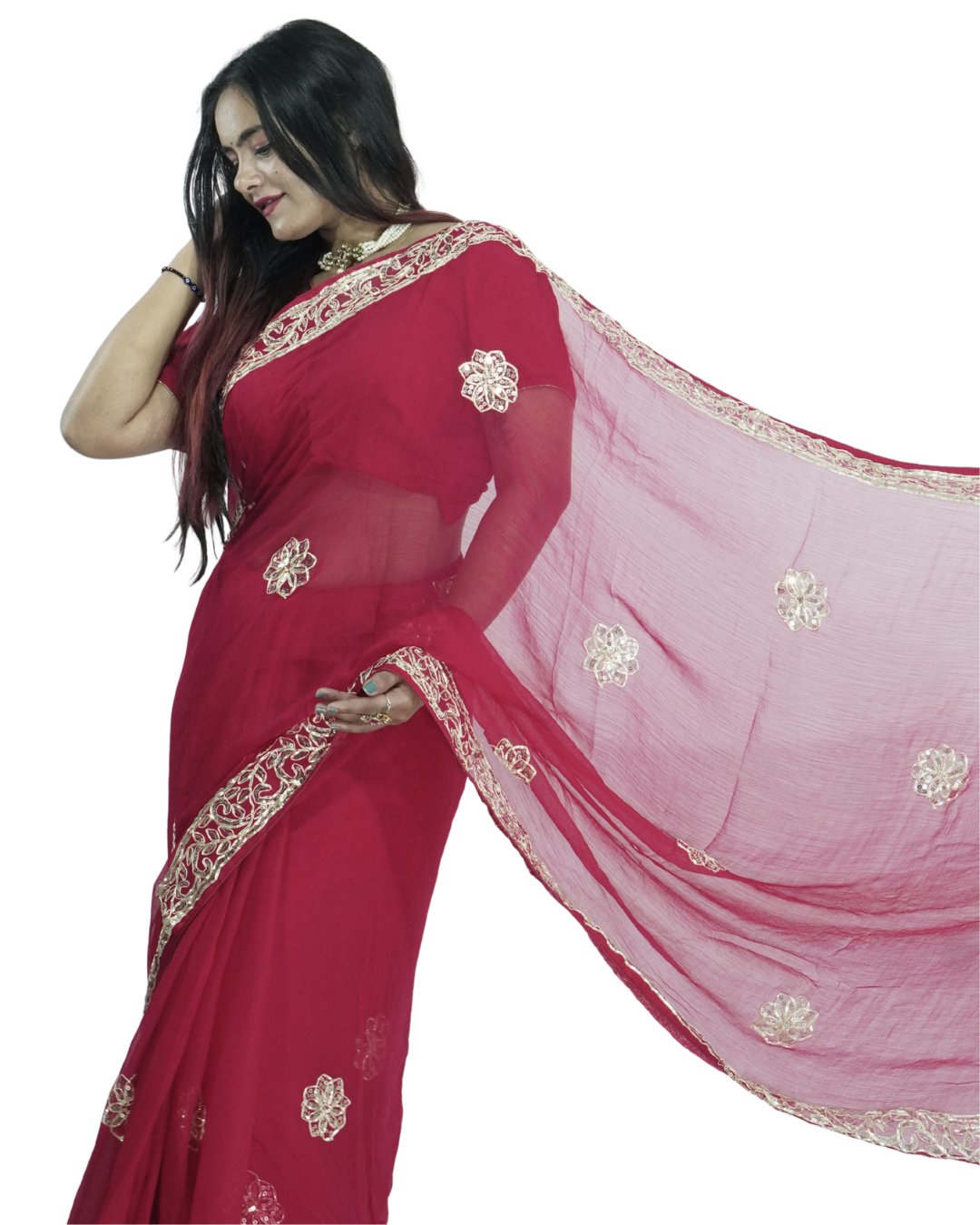 Woman modeling a deep red saree with delicate gold embroidered border and floral butta motifs, the sheer pallu flowing outward to showcase the intricate detailing and elegant drape. ✨