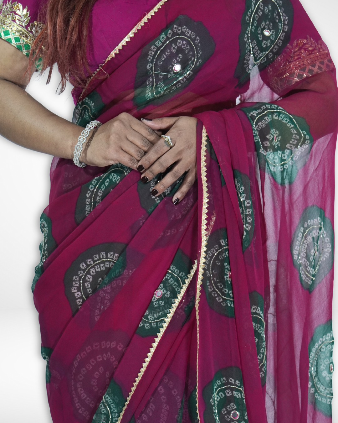 Close-up detail of a deep magenta chiffon saree featuring green bandhani-style circular motifs and a delicate gold border, highlighting the elegant drape and craftsmanship of Amai Jaipur’s festive designer saree. ✨