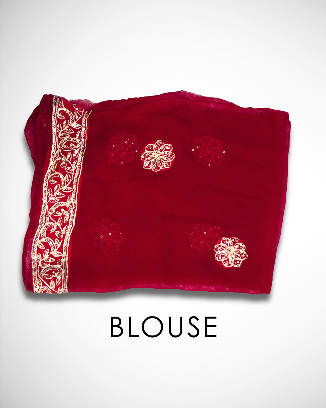 Folded deep red saree blouse fabric featuring gold embroidered floral motifs and a decorative gold vine border along the edge, displayed against a plain background. ✨