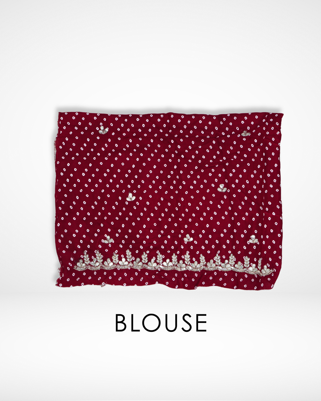 Folded red blouse fabric with small white dotted patterns and delicate gold embroidered floral border along the edge, designed to complement a saree, displayed against a plain background. ✨