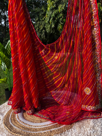 Vibrant Red Lehariya Pure Chiffon Saree featuring Heavy Kardhana and Gotta Patti Butta Work. Traditional Rajasthani handwork for wedding and festive wear. Saree plates hanging with the Rich and heavy Pallu of the saree