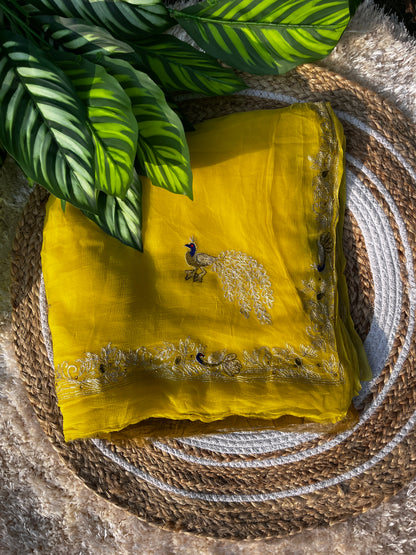 Lightweight Olive Green and Yellow Pure Chiffon Saree hand-embroidered with traditional Aari Tari and sparkling Peacock Aari Butta motifs, perfect for wedding wear. A picture of Saree when Folded properly.