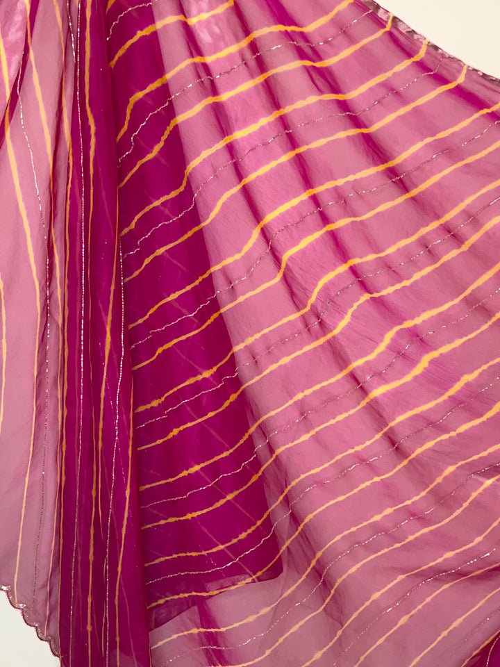 Close-up of a lightweight pink and magenta saree with soft yellow tie-dye style stripes and delicate silver shimmer lines, creating a flowing, airy look. ✨