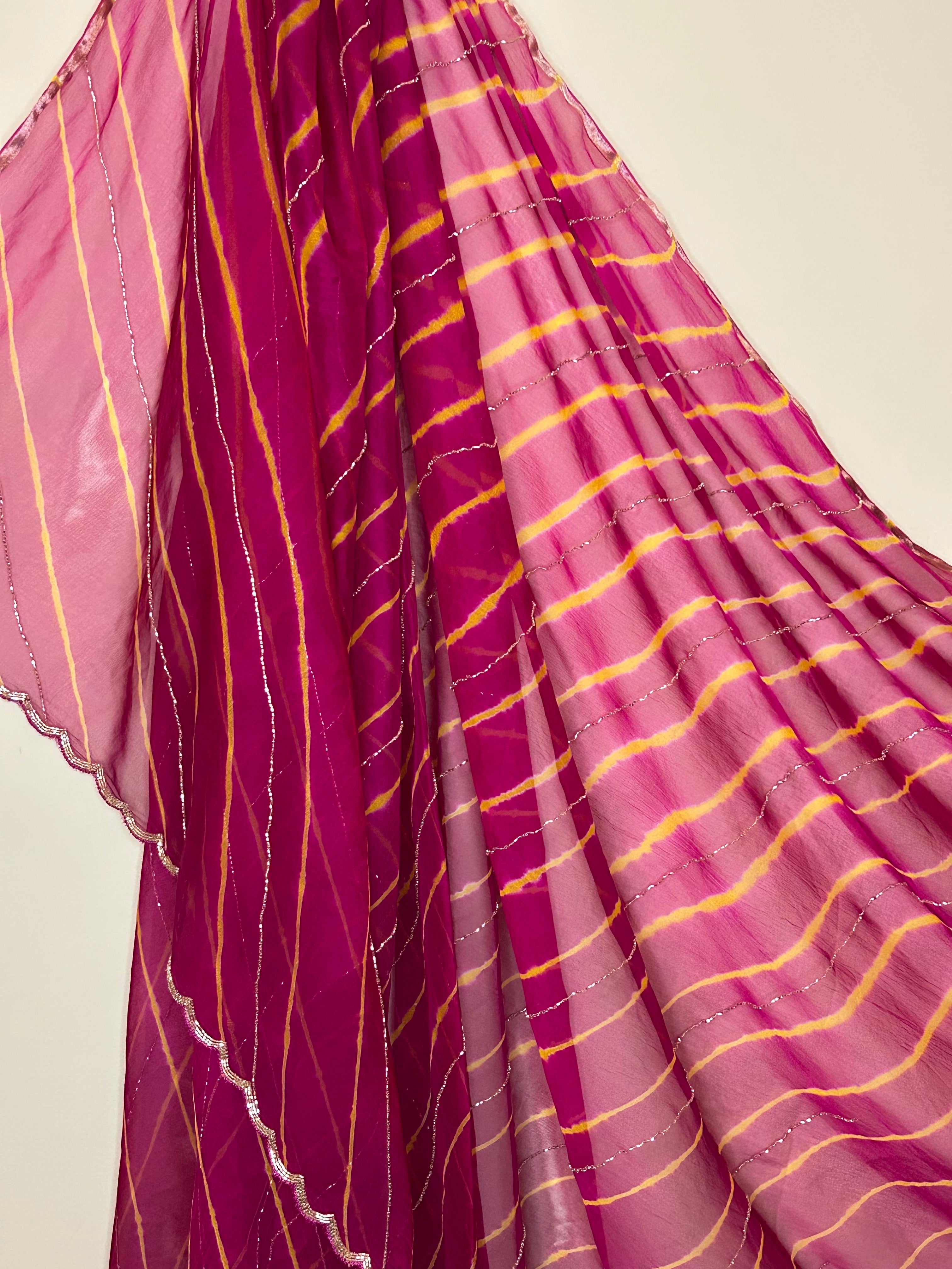 Flowing magenta and pink sheer saree featuring traditional tie-dye style diagonal stripes in yellow, accented with delicate silver shimmer lines and a subtle scalloped border. ✨