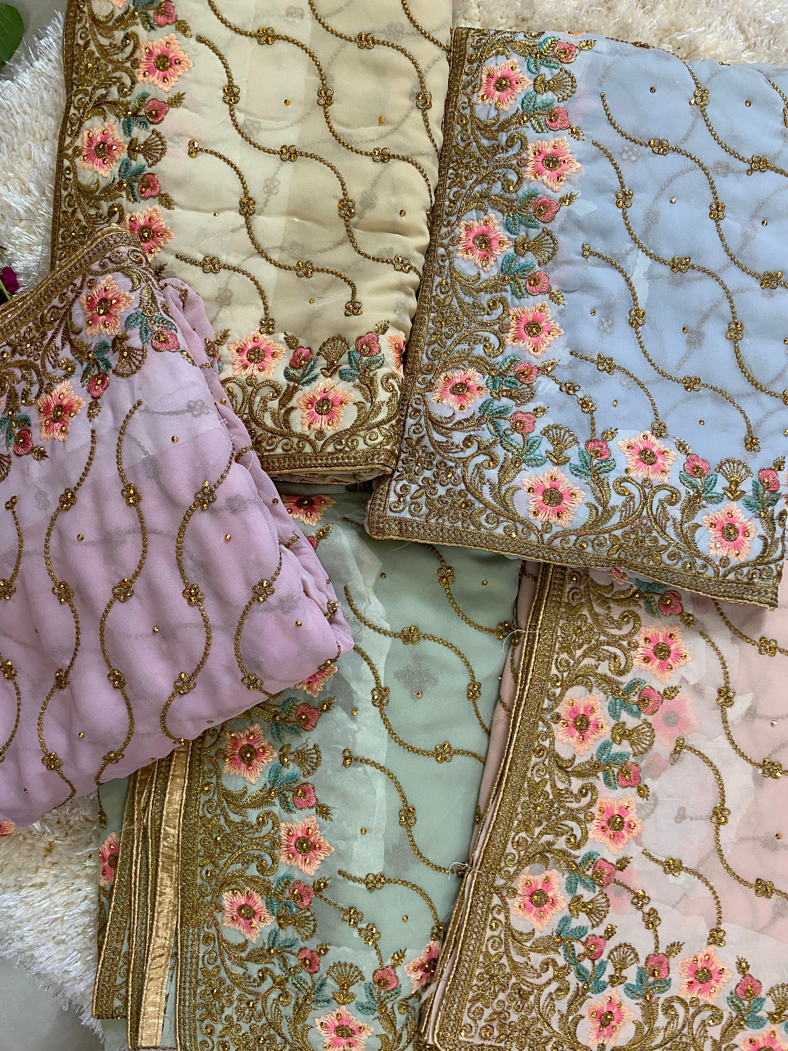 Collection of pastel sarees in soft shades of lavender, mint green, cream, blush pink, and powder blue, each featuring intricate gold thread embroidery with pink floral motifs and delicate vine patterns, arranged together to showcase the color variations. ✨
