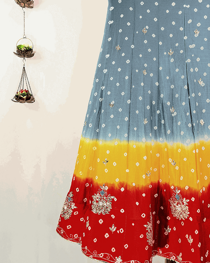 Close-up view of the multicolored Rajasthani Bandhani Lehenga skirt flare, highlighting the heavy floral Gota Patti border embroidery on vibrant pink, orange, and green Bandhej fabric, suitable for wedding and festive wear.